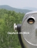Deutsch im Blick textbook cover with a German forest and mountain landscape and a public binocular in the front. There is a German flag on the left lens